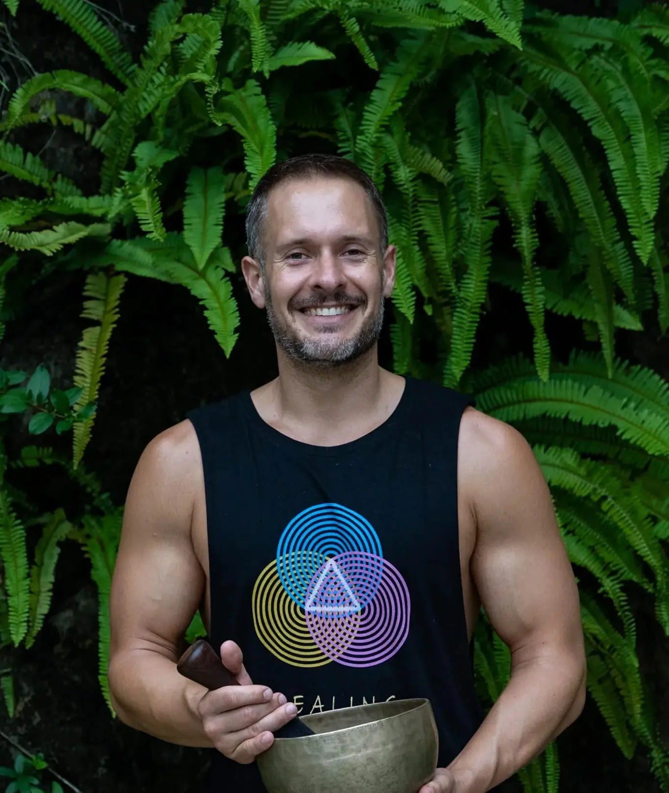 Alex Bastianon in a black singlet holding a metal tibetan singing bowl