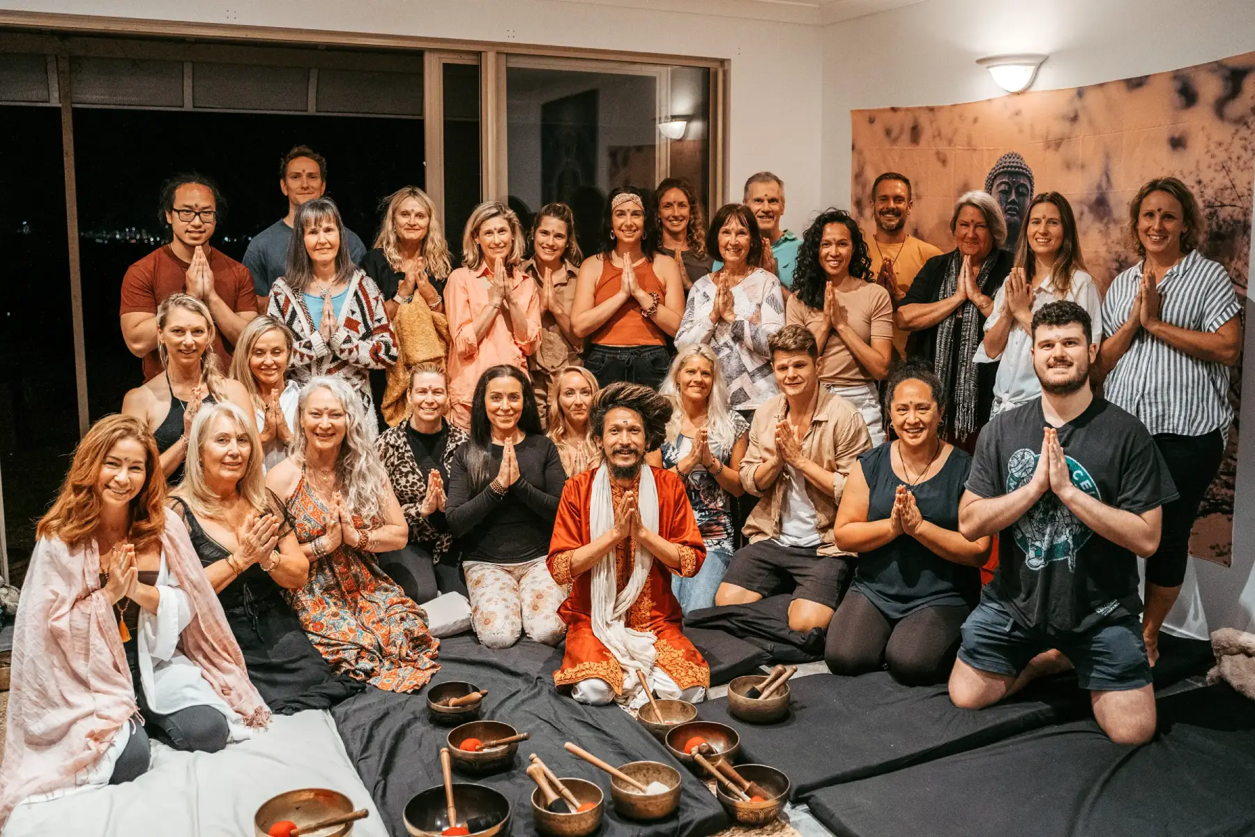 Group picture of Sound healer Chaitanyashree, Alex Bastianon and a group of smiling people with hands in prayer position